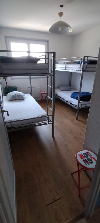 La chambre "city" Chambre avec lits superposés, matelas, et espace au sol en bois.