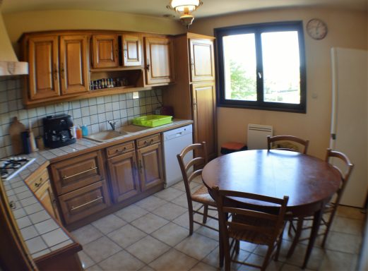 Espace cuisine Cuisine chaleureuse avec armoires en bois, une table ronde et une fenêtre laissant entrer la lumière.